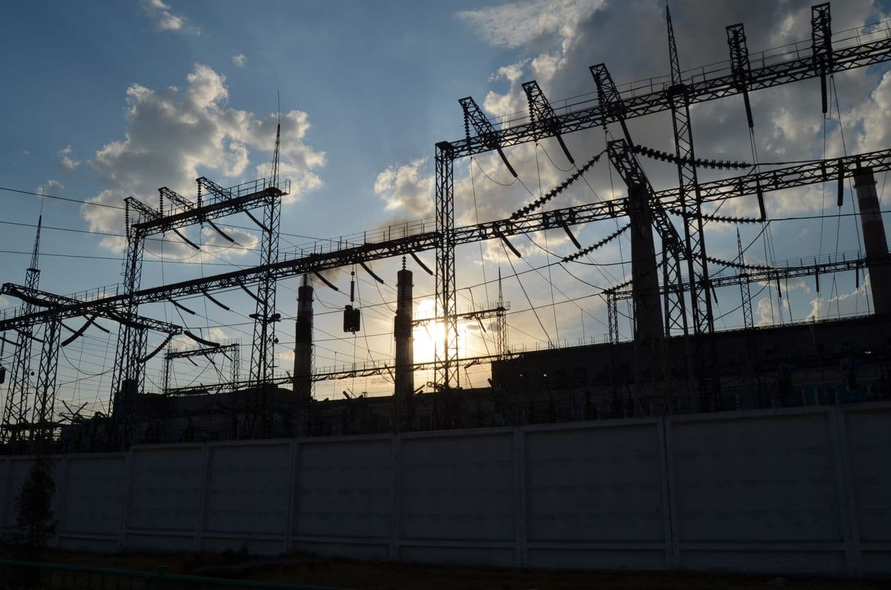 Electrical substation gantries silhouetted against a dusk sky.