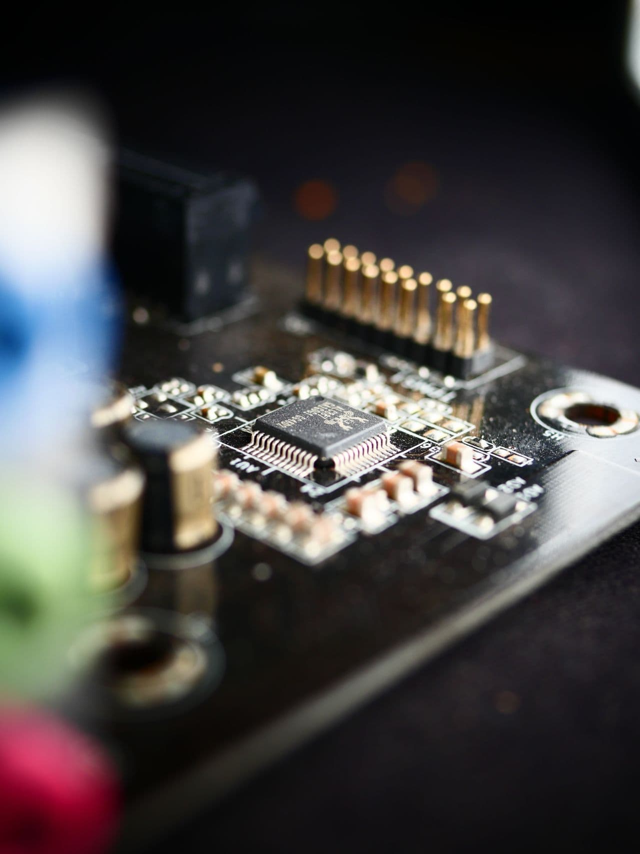 Macro photograph of a surface-mount chip beside a pin header.