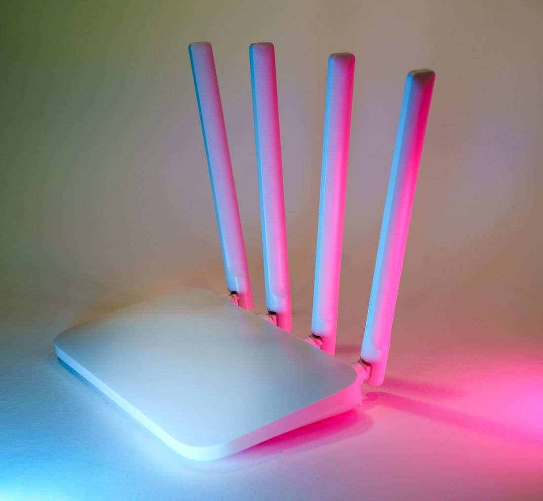 A wireless router with four antennas lit in coloured light.