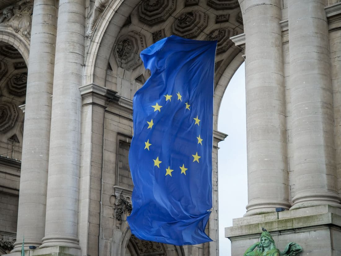 A European Union flag hanging beneath a stone arch in Brussels.